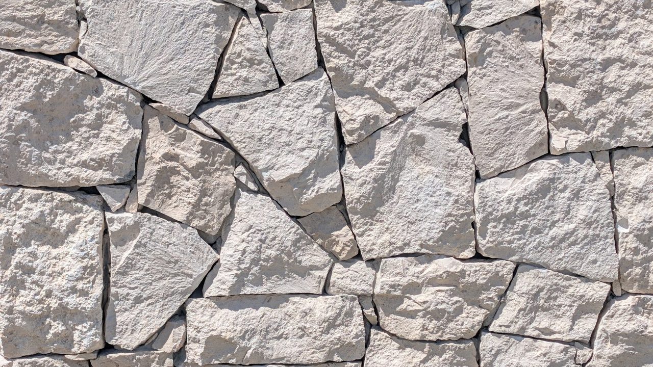 Close-up van Luminous Ivory kalksteen met een natuurlijk breukvlak, waarbij gebroken steenvlakken in reliëf liggen